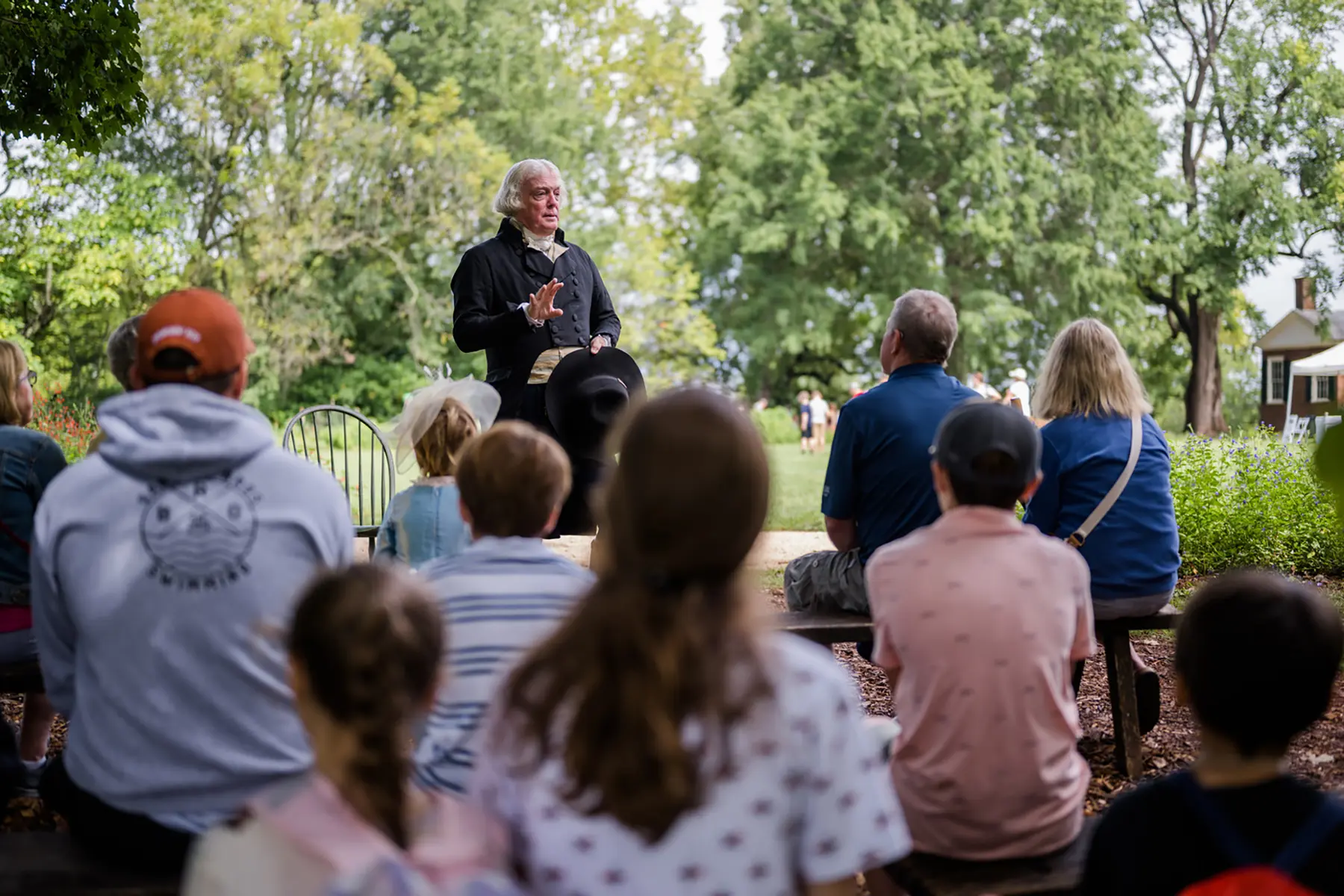 Thomas Jefferson, portrayed by Bill Barker, speaks before a group of seated visitors to Monticello.
