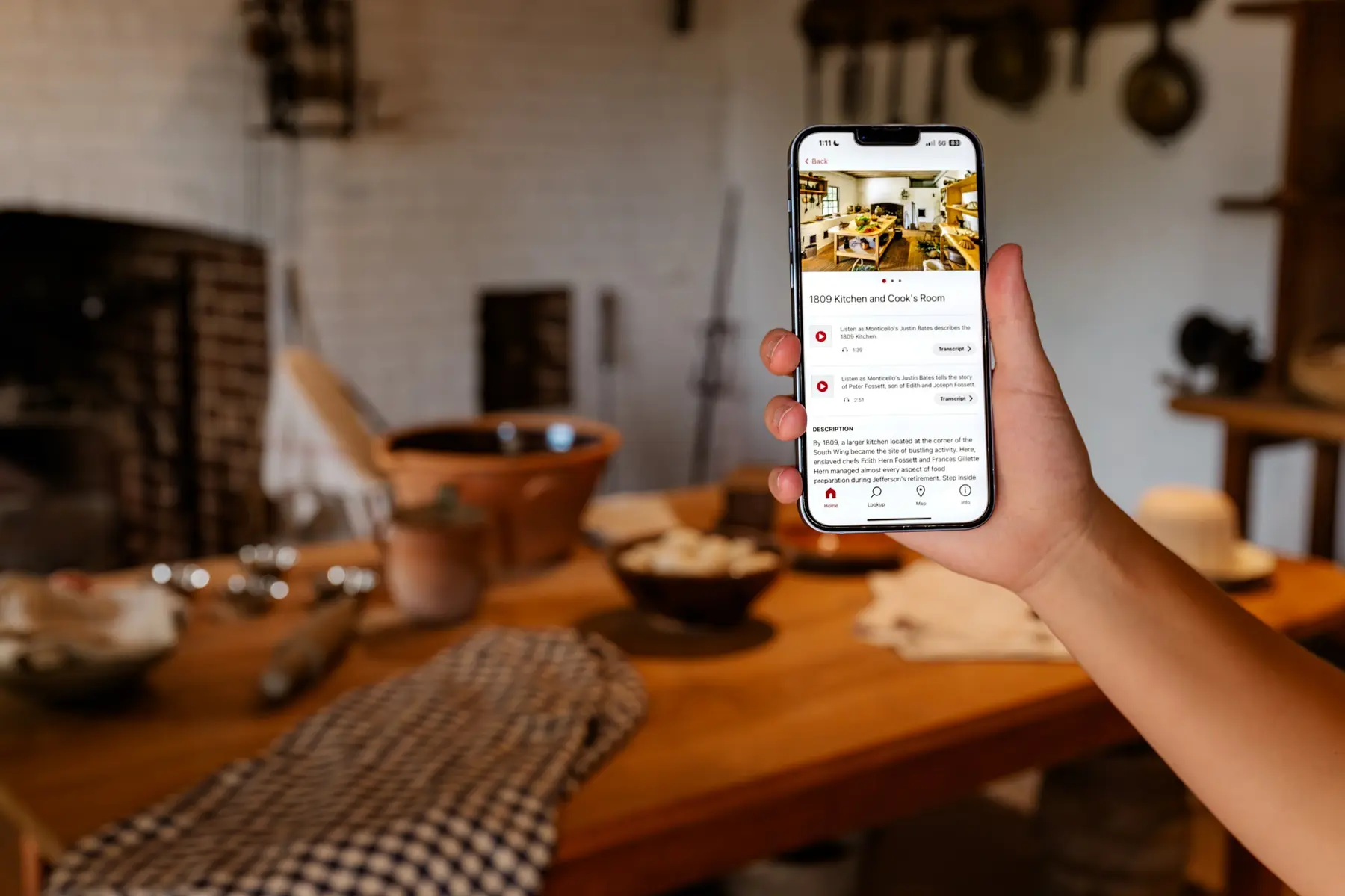 The cook's kitchen in the background with a person holding a cellphone in the foreground.